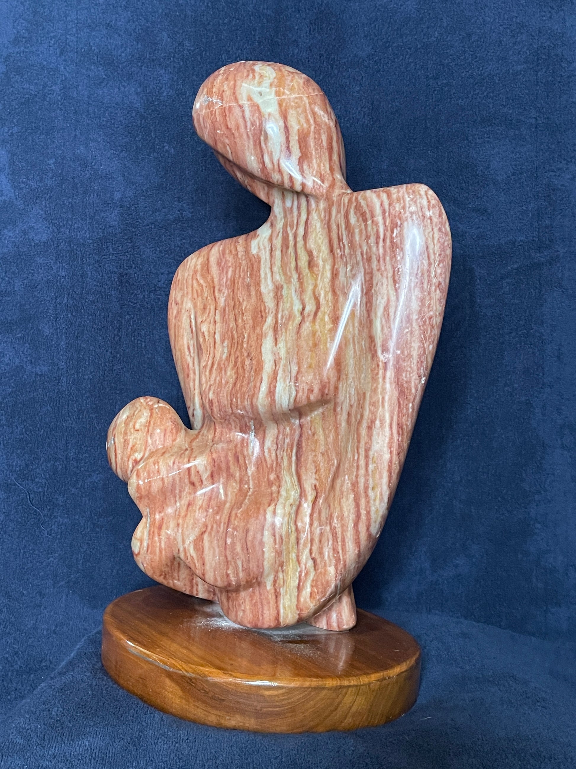 Cherish is carved from Utah red alabaster. Its smooth surface conveys a sense of tranquility and grace. represents the eternal bond of love between a mother and child. This is the first time a human being experiences love through the gentle touch of his/her mother. That is an everlasting love for both of them.

This sculpture was designed and carved by Shahla Rahimi Reynolds.

This piece is: 10" Width x 17 1/2" Height x 6 1/2" Depth.