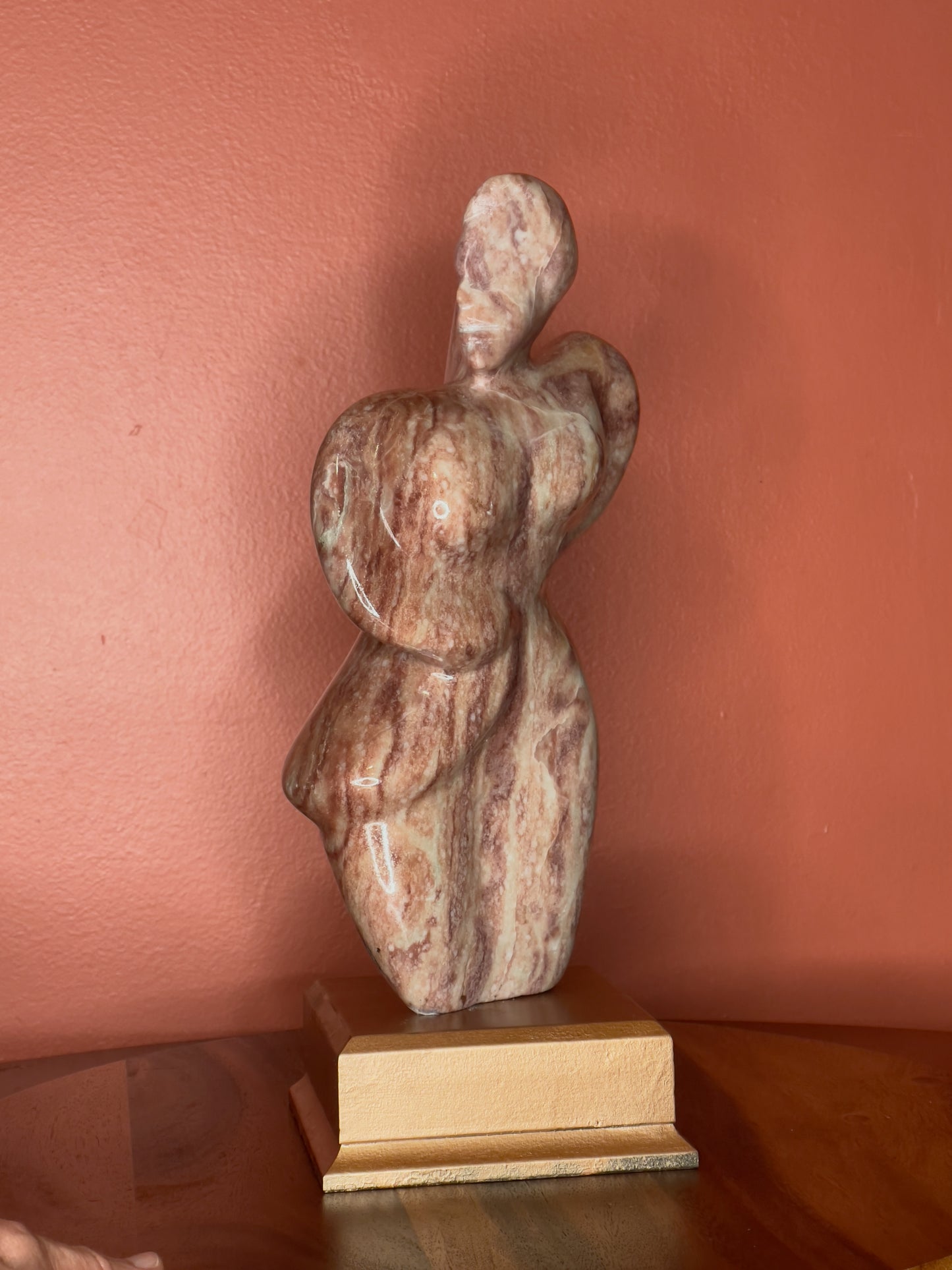 A hand-carved Utah alabaster sculpture depicting Venustus (pronounced veh-NUSS-tuss), the Goddess of Love, showcasing an elegant and refined female form. It represents the qualities of beauty, confidence, and self-assurance, embodying a woman who confidently navigates her own journey through life. The sculpture reflects themes of independence and personal strength, celebrating resilience and empowerment.

Venustus is an original design created by Shahla Rahimi Reynolds.

The piece is 13" H x 8" W x 3.5" D.