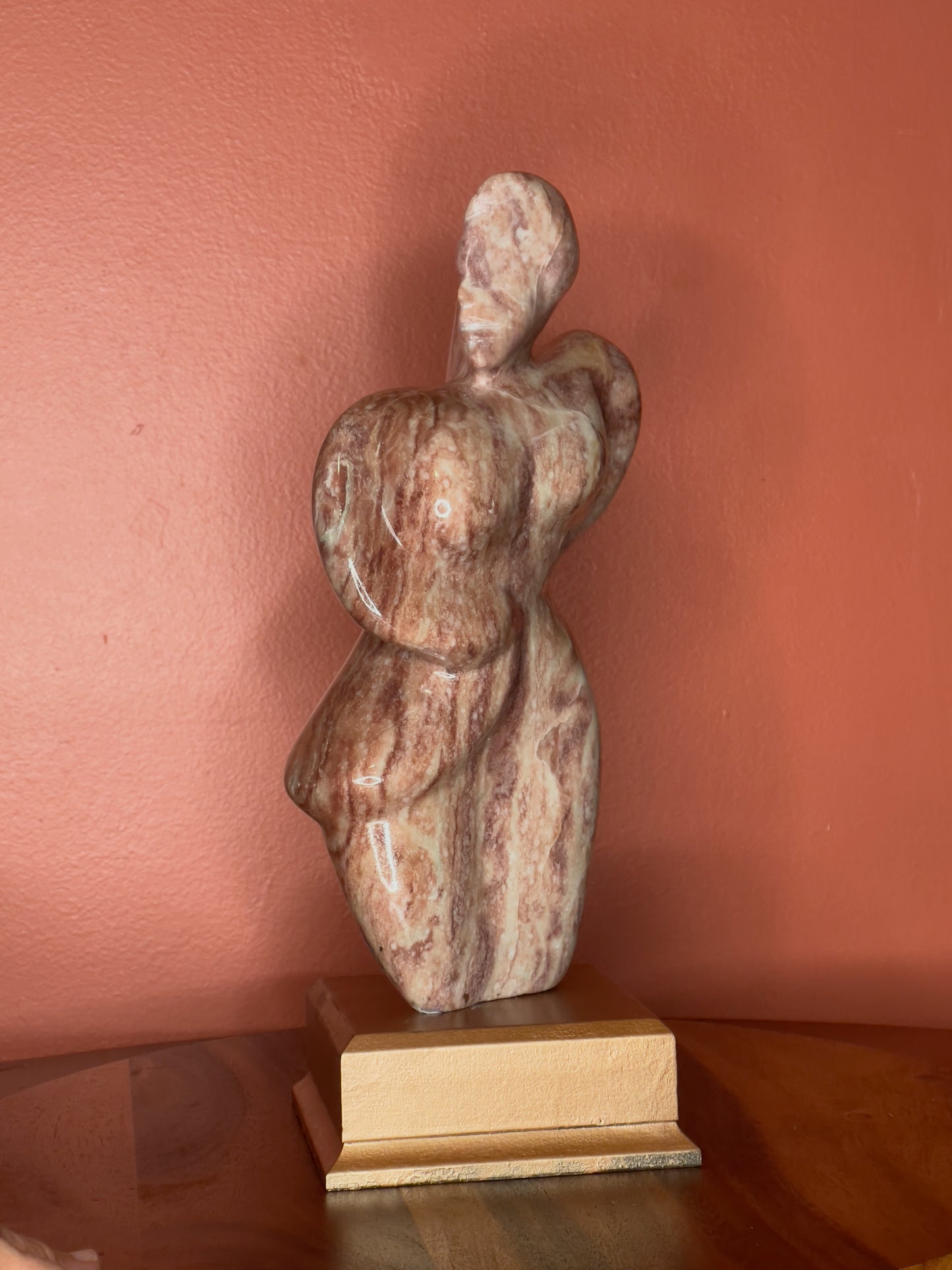 A hand-carved Utah alabaster sculpture depicting Venustus (pronounced veh-NUSS-tuss), the Goddess of Love, showcasing an elegant and refined female form. It represents the qualities of beauty, confidence, and self-assurance, embodying a woman who confidently navigates her own journey through life. The sculpture reflects themes of independence and personal strength, celebrating resilience and empowerment.

Venustus is an original design created by Shahla Rahimi Reynolds.

The piece is 13" H x 8" W x 3.5" D.