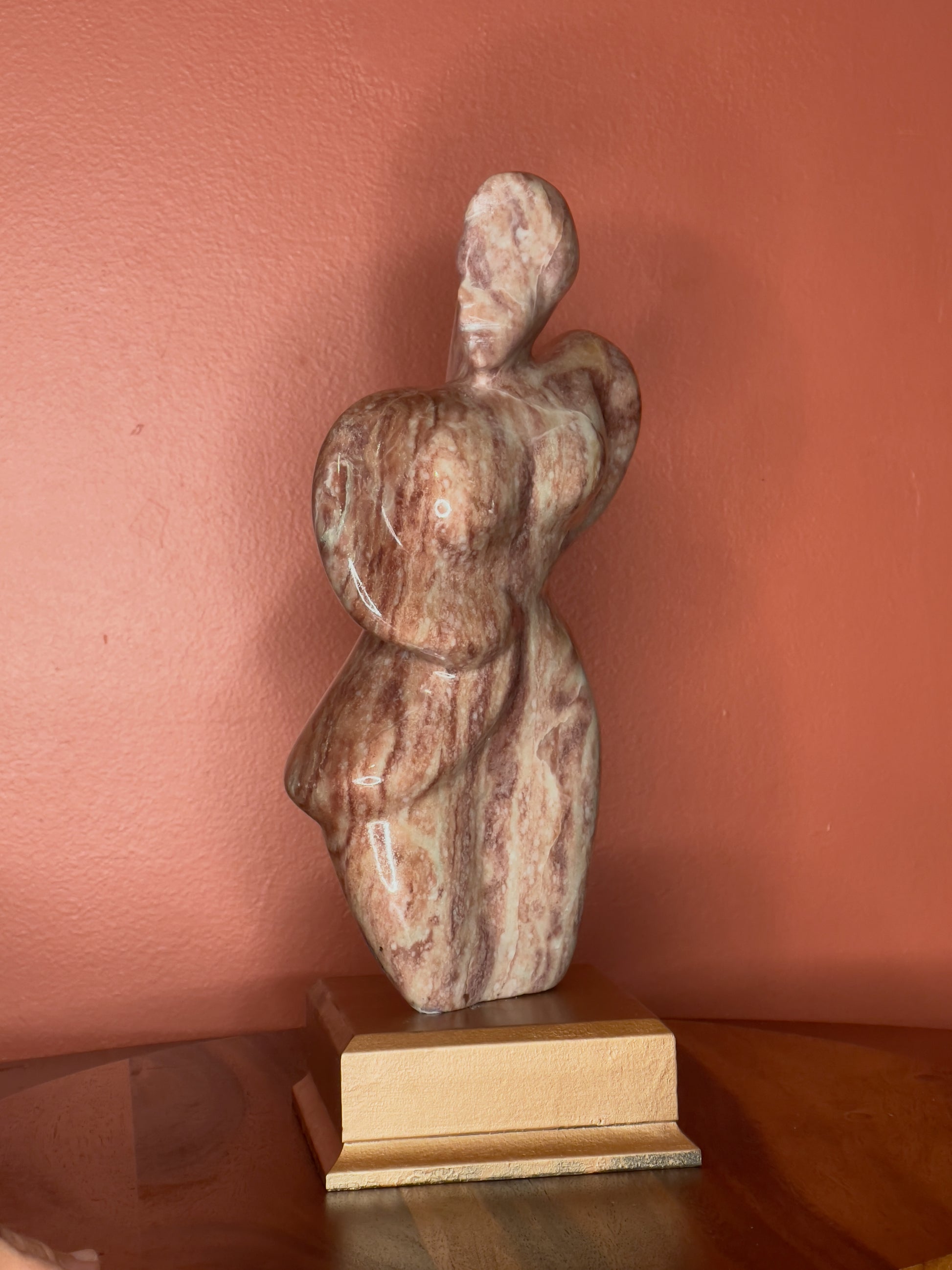 A hand-carved Utah alabaster sculpture depicting Venustus (pronounced veh-NUSS-tuss), the Goddess of Love, showcasing an elegant and refined female form. It represents the qualities of beauty, confidence, and self-assurance, embodying a woman who confidently navigates her own journey through life. The sculpture reflects themes of independence and personal strength, celebrating resilience and empowerment.

Venustus is an original design created by Shahla Rahimi Reynolds.

The piece is 13" H x 8" W x 3.5" D.