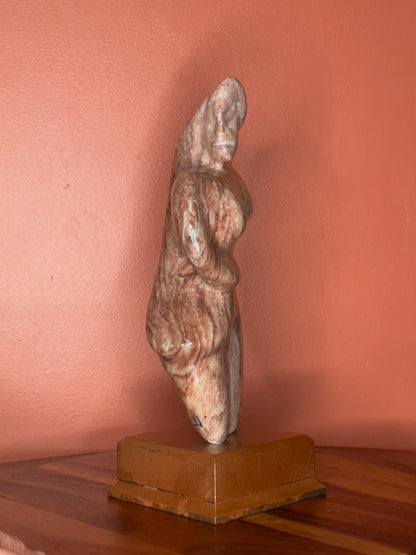 A hand-carved Utah alabaster sculpture depicting Venustus (pronounced veh-NUSS-tuss), the Goddess of Love, showcasing an elegant and refined female form. It represents the qualities of beauty, confidence, and self-assurance, embodying a woman who confidently navigates her own journey through life. The sculpture reflects themes of independence and personal strength, celebrating resilience and empowerment.

Venustus is an original design created by Shahla Rahimi Reynolds.

The piece is 13" H x 8" W x 3.5" D.