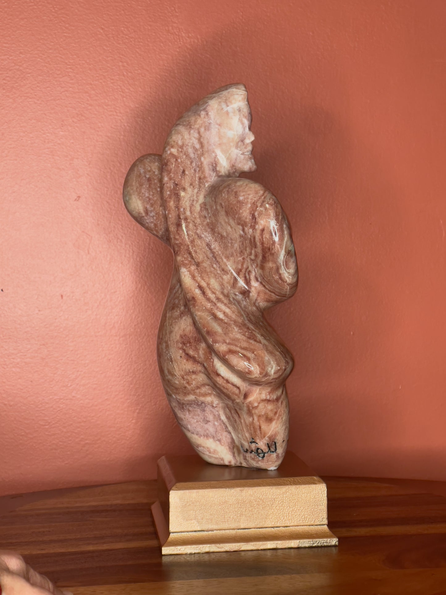A hand-carved Utah alabaster sculpture depicting Venustus (pronounced veh-NUSS-tuss), the Goddess of Love, showcasing an elegant and refined female form. It represents the qualities of beauty, confidence, and self-assurance, embodying a woman who confidently navigates her own journey through life. The sculpture reflects themes of independence and personal strength, celebrating resilience and empowerment.

Venustus is an original design created by Shahla Rahimi Reynolds.

The piece is 13" H x 8" W x 3.5" D.