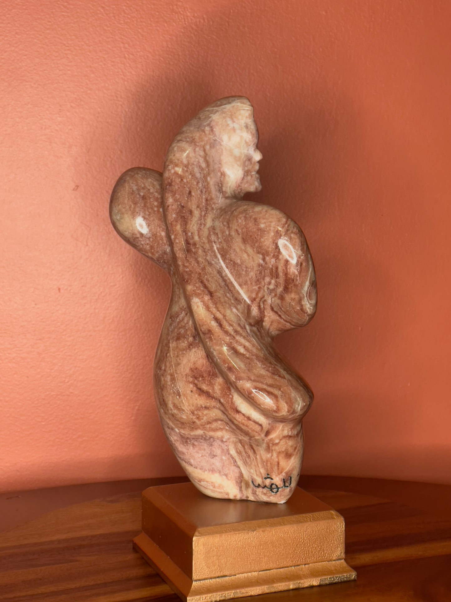 A hand-carved Utah alabaster sculpture depicting Venustus (pronounced veh-NUSS-tuss), the Goddess of Love, showcasing an elegant and refined female form. It represents the qualities of beauty, confidence, and self-assurance, embodying a woman who confidently navigates her own journey through life. The sculpture reflects themes of independence and personal strength, celebrating resilience and empowerment.

Venustus is an original design created by Shahla Rahimi Reynolds.

The piece is 13" H x 8" W x 3.5" D.